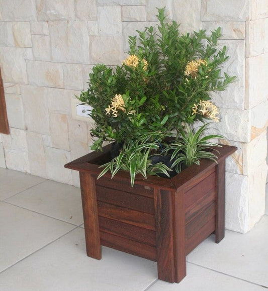 DIY wooden outdoor planter box built from 1x4 lumber, placed on a patio with plants